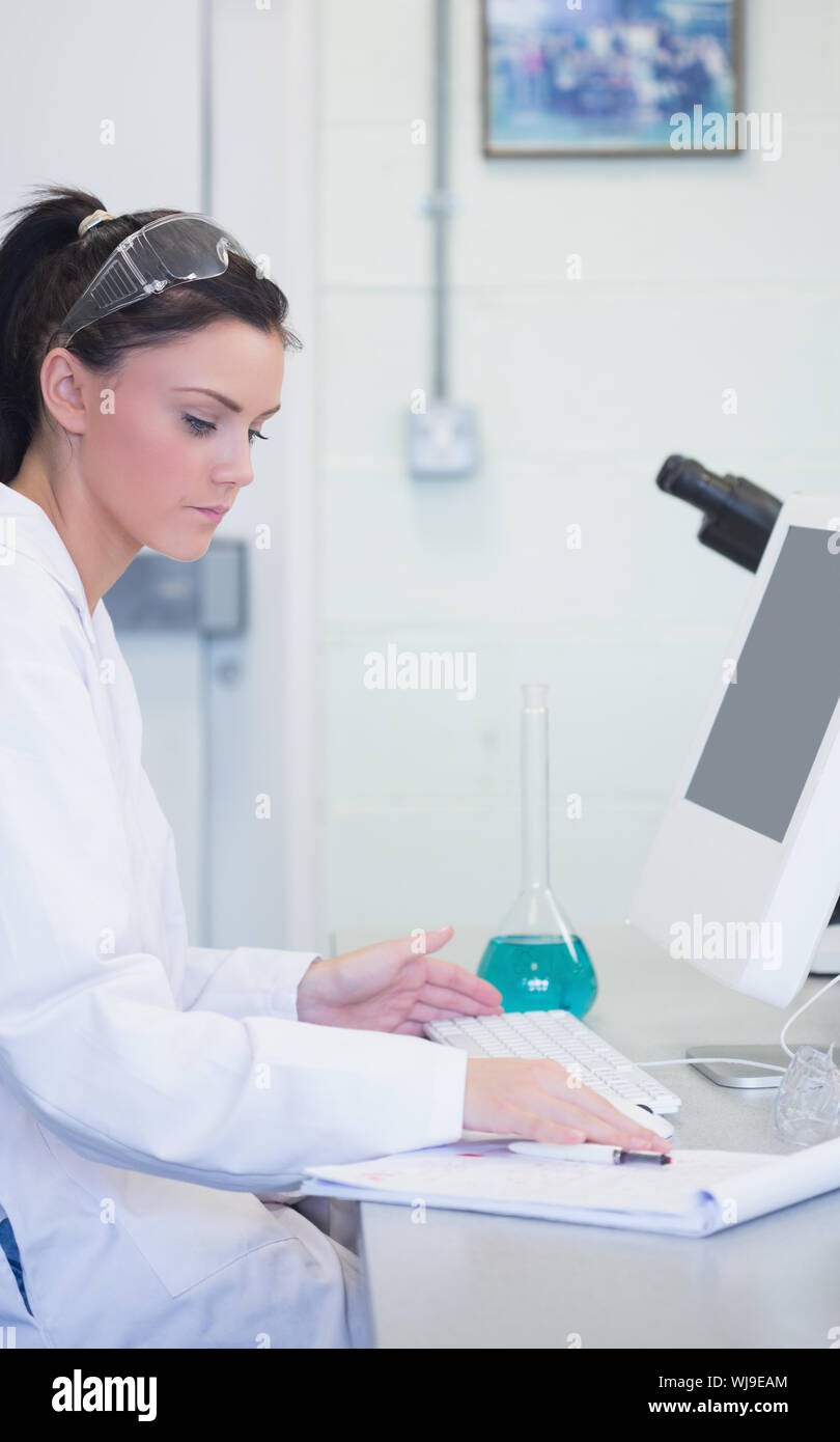 Side view of a young female researcher using computer in the laboratory ...