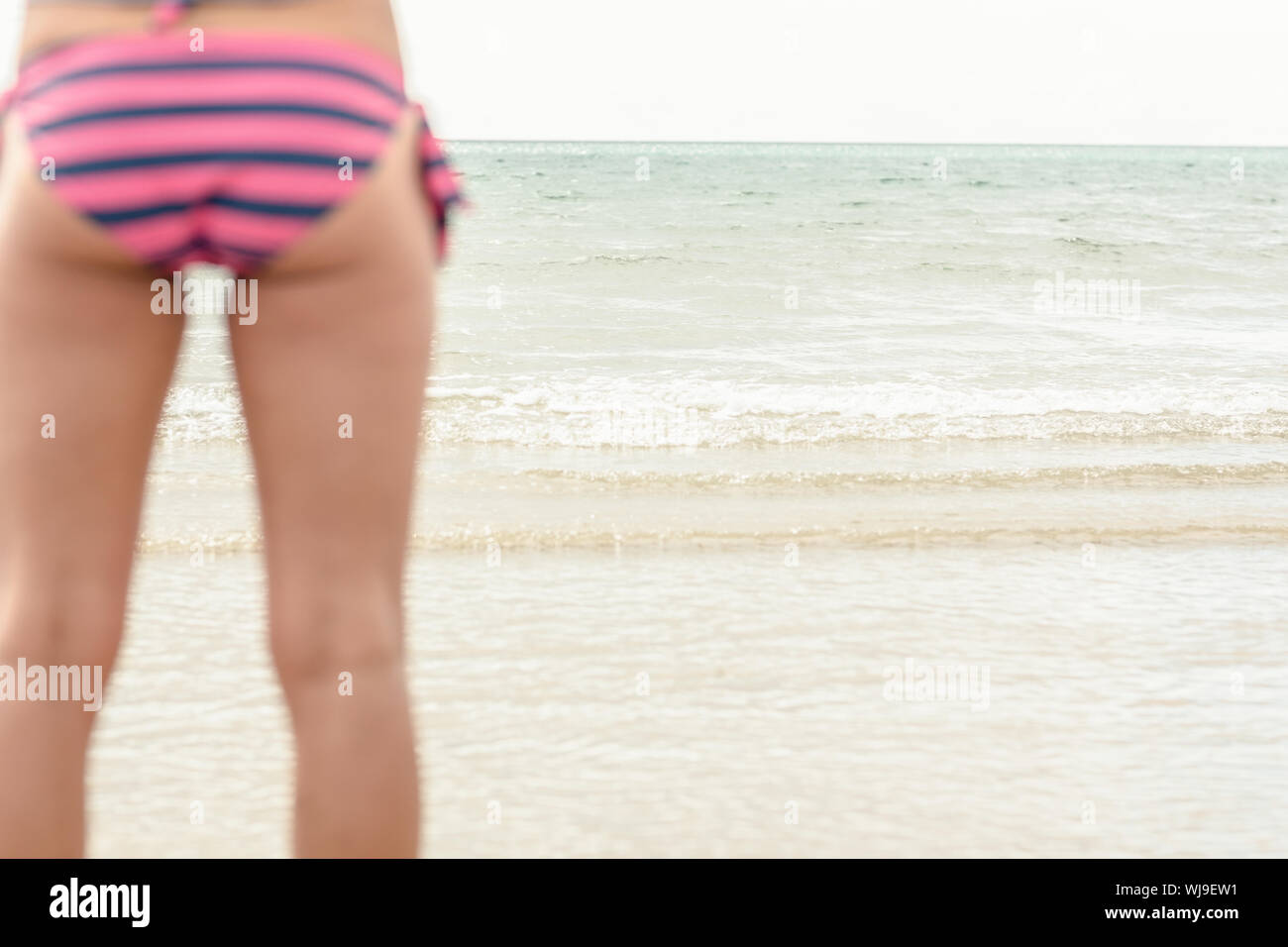 Rear view mid section of a slender woman in striped bikini bottom standing  on beach Stock Photo - Alamy