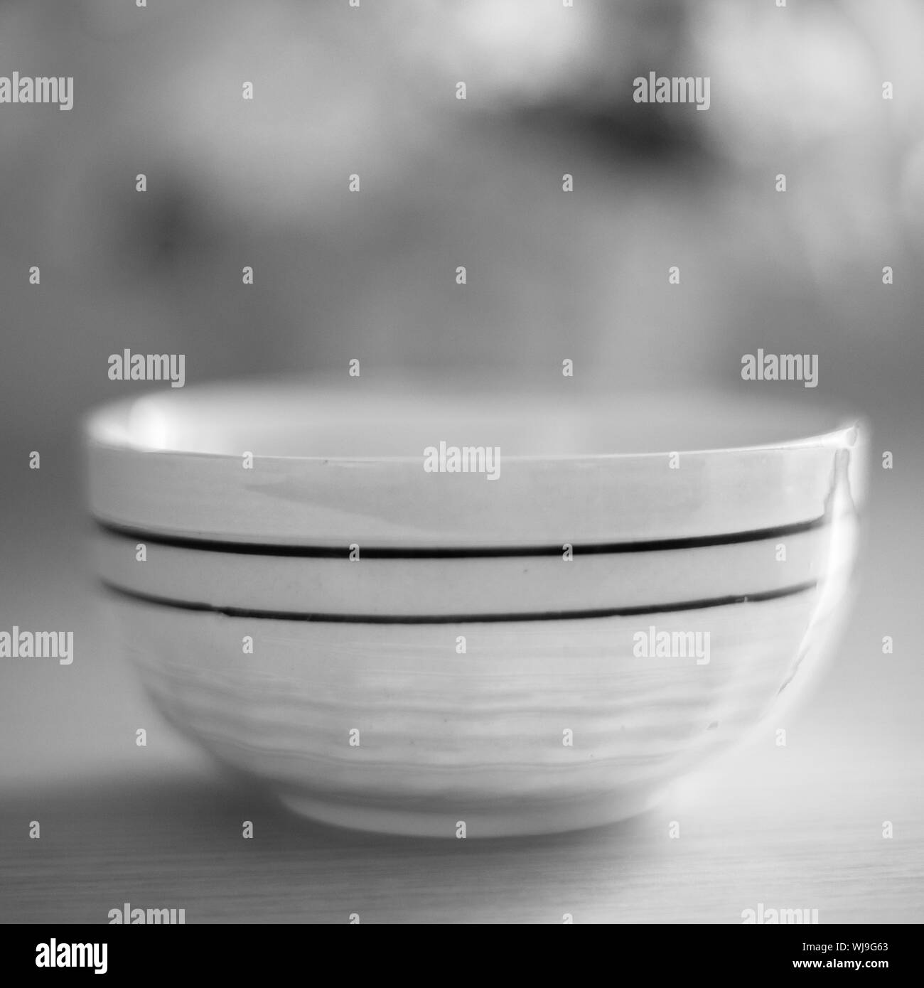 ceramic bowl with a striped pattern on the table, bw photo, soft selective focus. Stock Photo