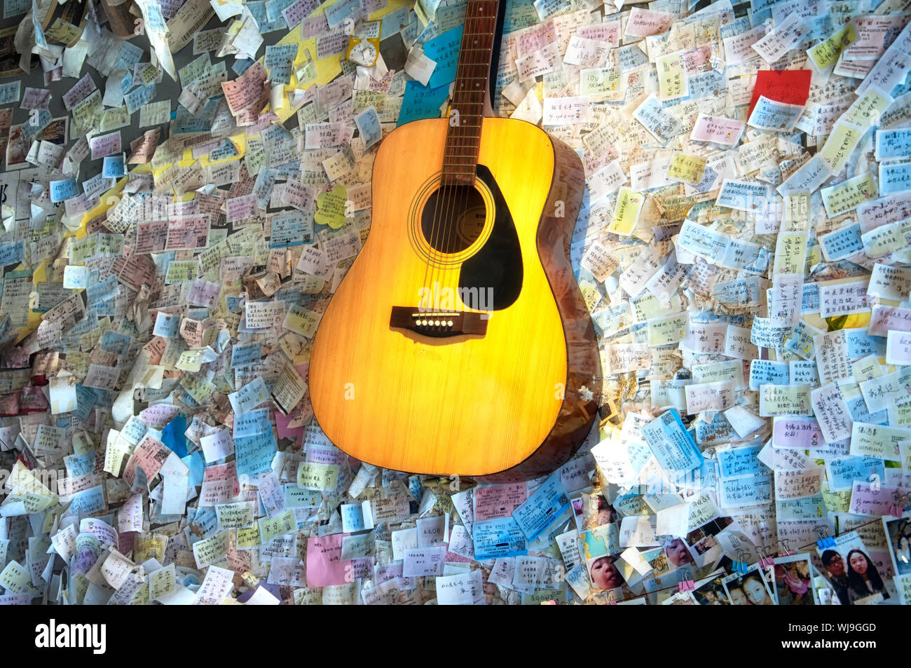 Fenghuang, China.  September 13, 2015. A acoustic guitar hanging on a wall with sticky notes and train tickets in a coffee shop within Fenghuang ancie Stock Photo