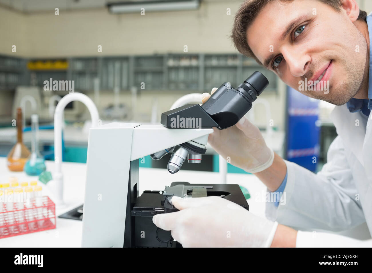 Closeup portrait of a male scientific researcher using microscope in the laboratory Stock Photo