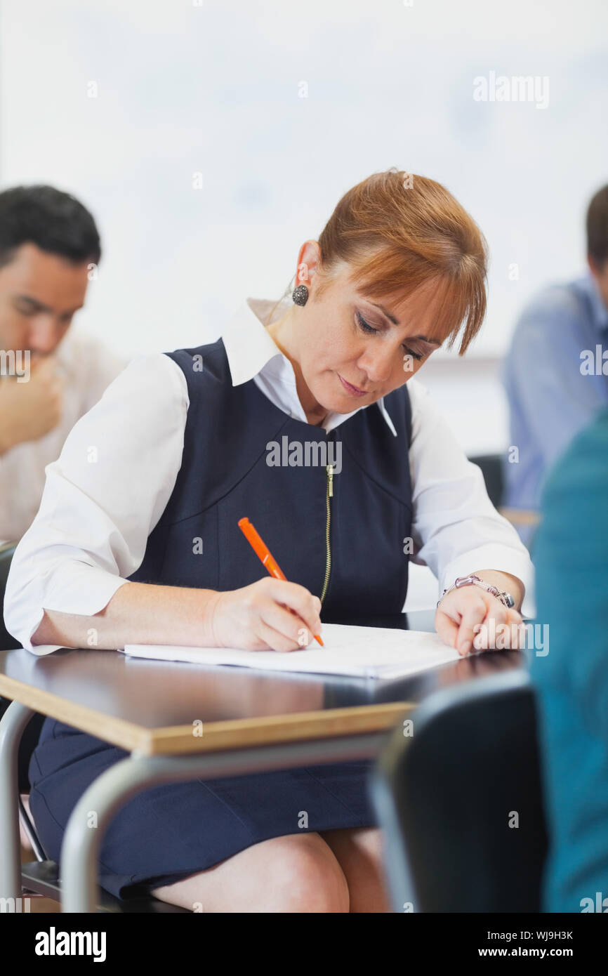 Concentrated female mature student sitting in classroom while learning Stock Photo