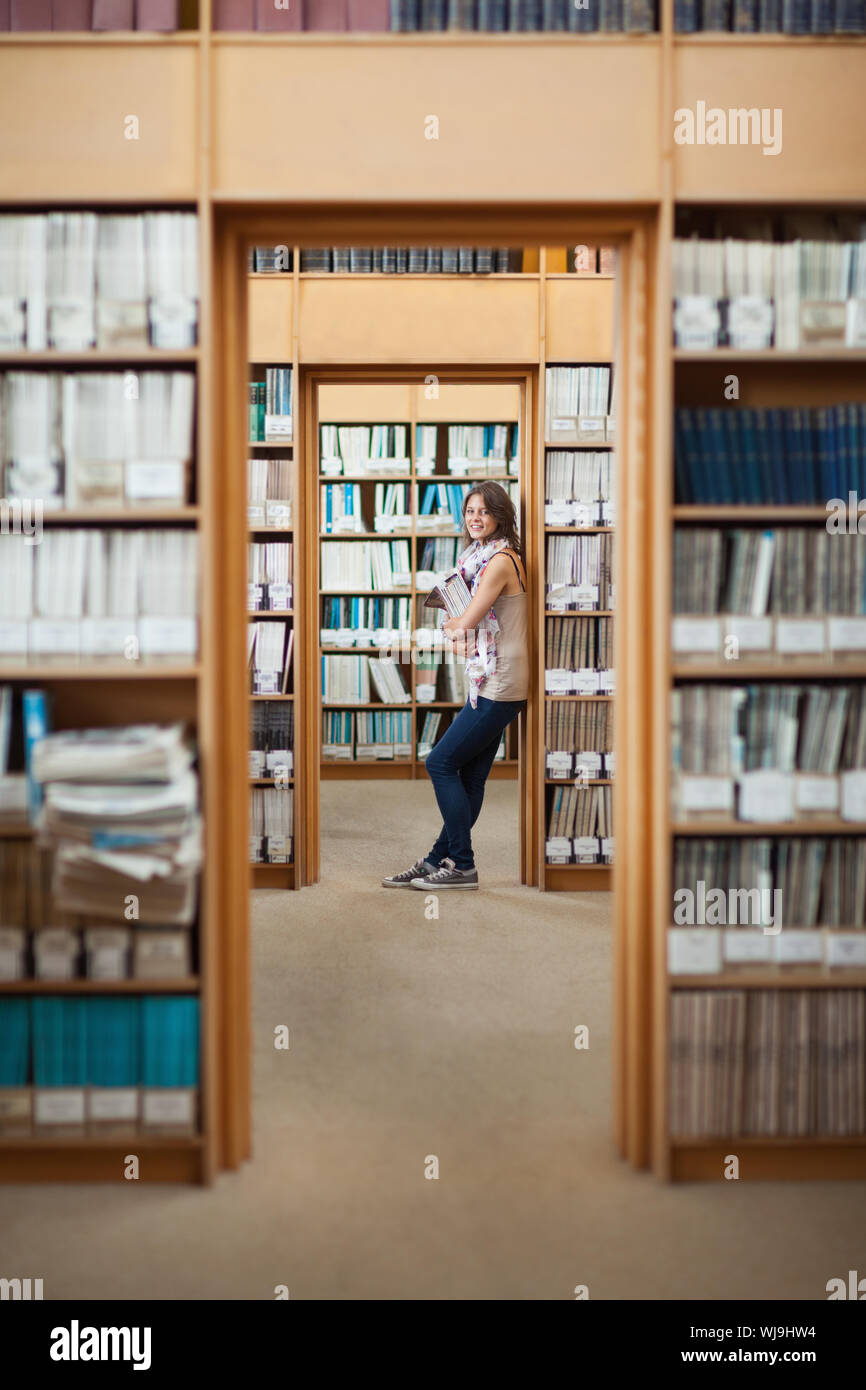 Full length side view of a smiling female student standing in the ...