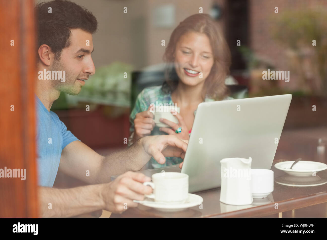 Two laughing students working at laptop in college canteen Stock Photo