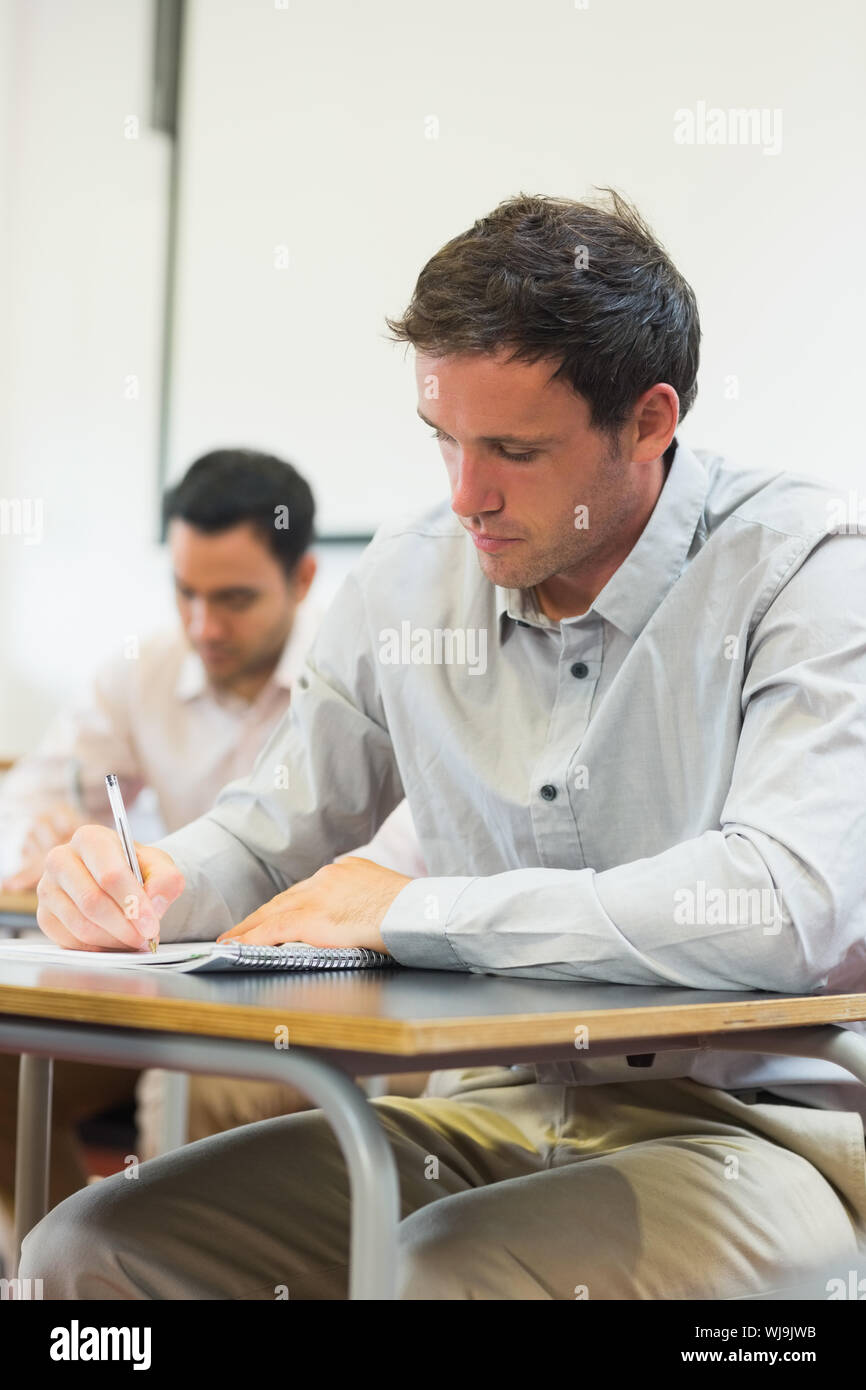 Mature students taking notes in lecture in college Stock Photo