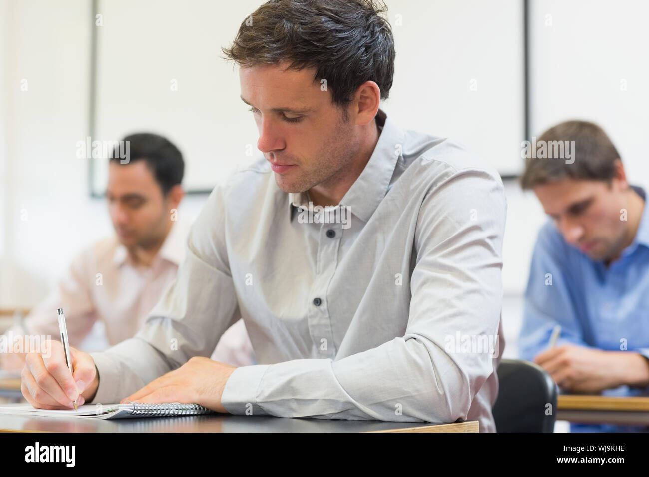 Three mature students taking notes in lecture in college Stock Photo