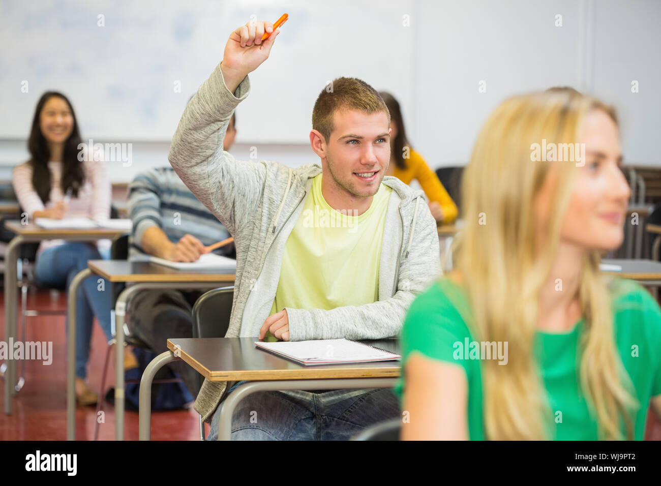 Young Male Student Raising Hand By Others In The College Classroom Stock Photo Alamy