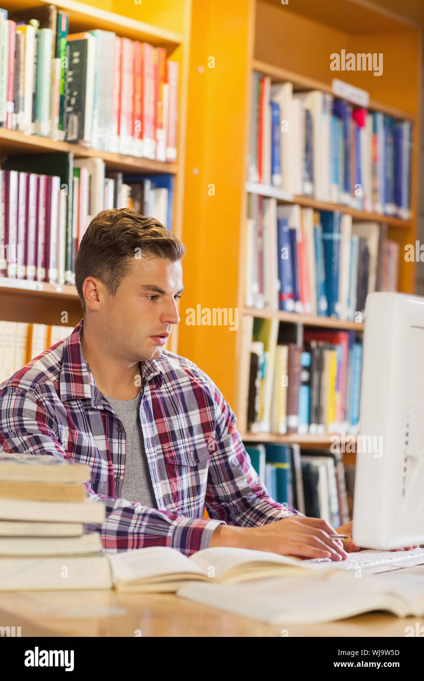 Handsome concentrating student using computer in library Stock Photo ...