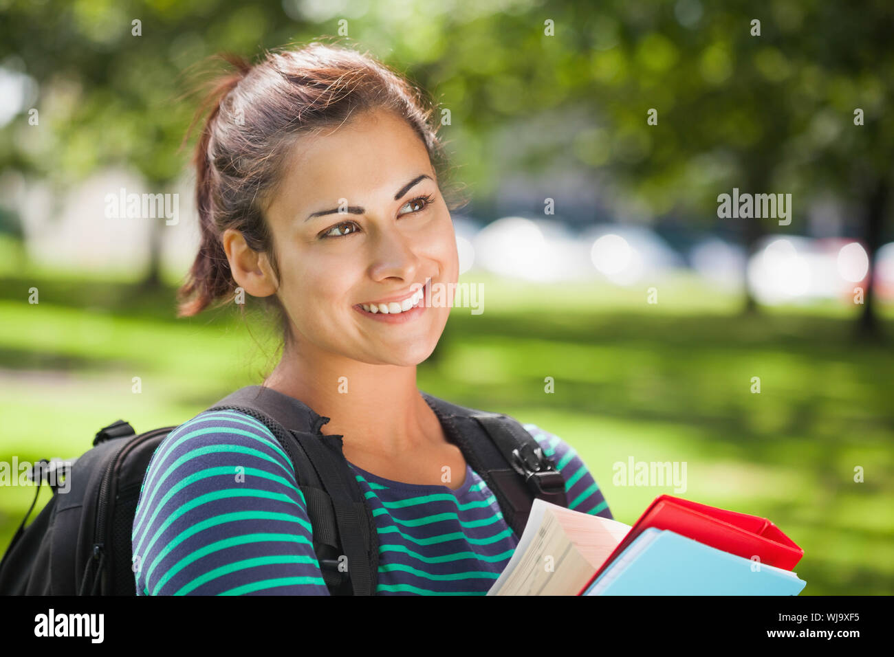 Casual smiling student holding books on campus at college Stock Photo ...