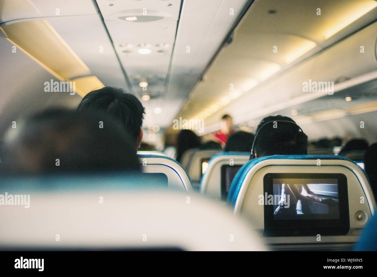 interior of a plane with tv screen for in flight entertainment. Stock Photo