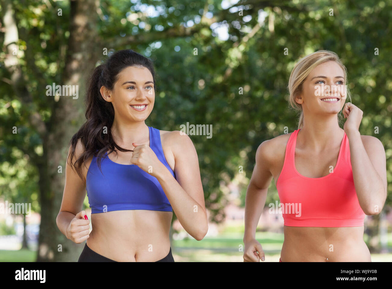 Two Sporty Women Jogging In A Park Wearing Sports Bras Stock Photo