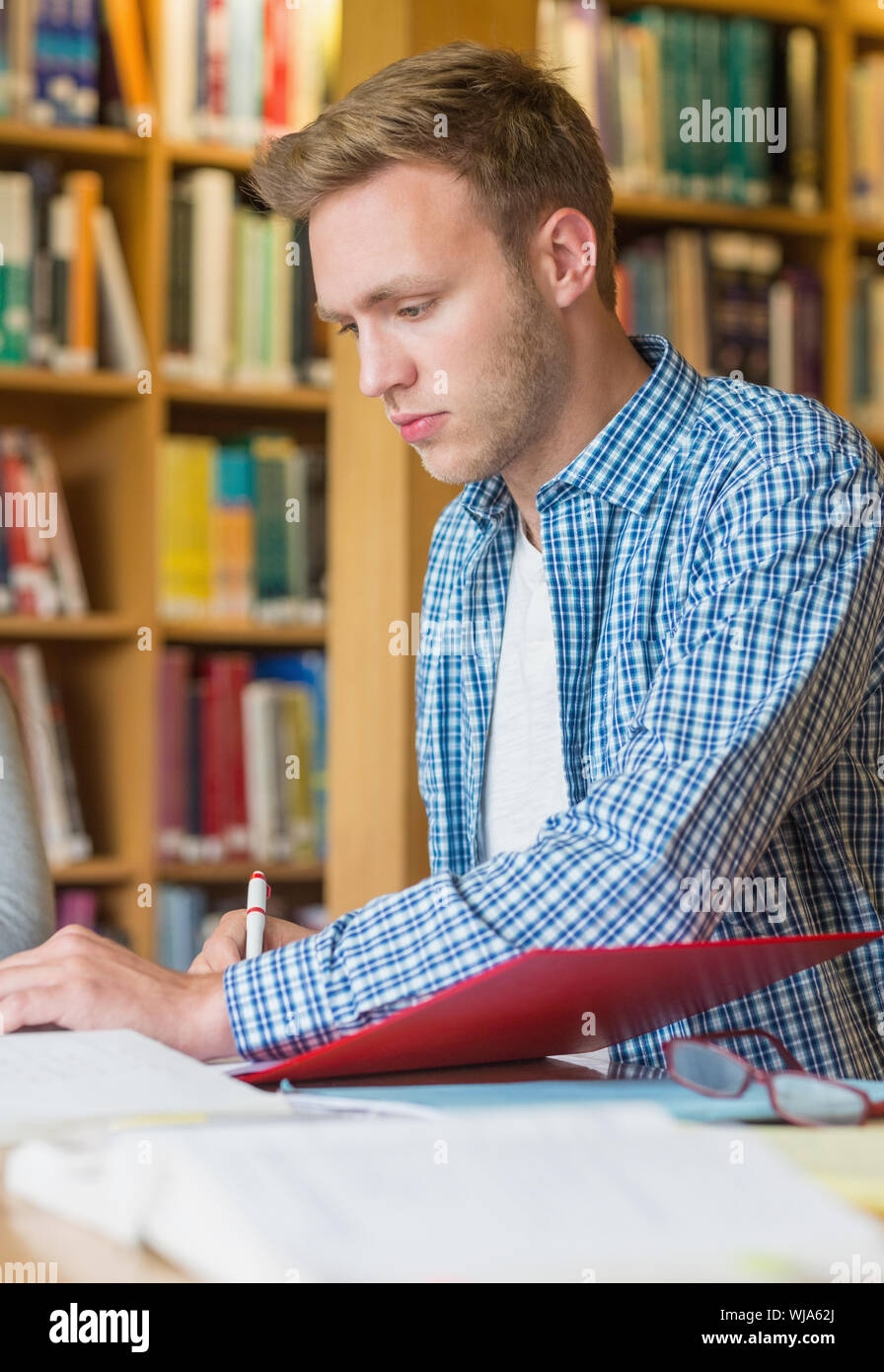 Young male student writing notes at desk in the college library Stock ...