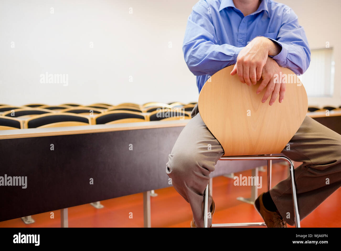 Mid section of a male teacher sitting on chair in the lecture hall