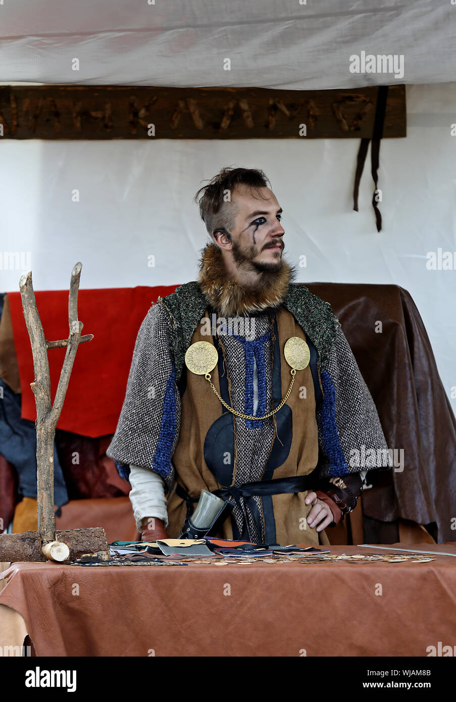 Hameenlinna Finland 08/17/2019 Medieval festival with craftsman, knights and entertainers.  A young man in medieval costume selling his handwork in ma Stock Photo