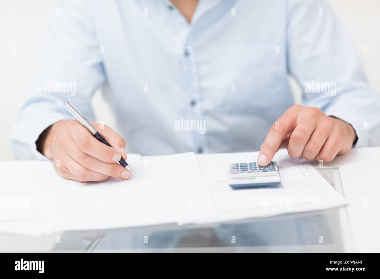 Mid section of a young man with bills and calculator Stock Photo