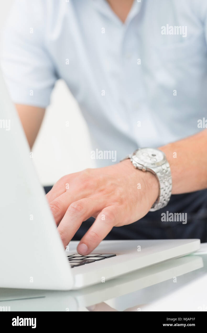 Mid section of a man using laptop on coffee table Stock Photo