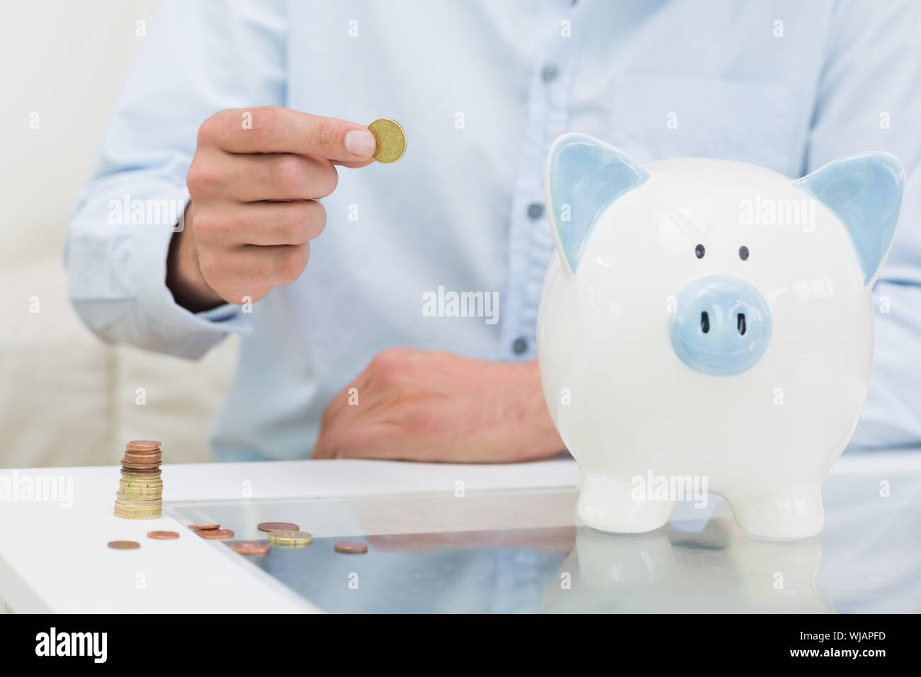 Mid section of a man putting some coins into a piggy bank Stock Photo ...