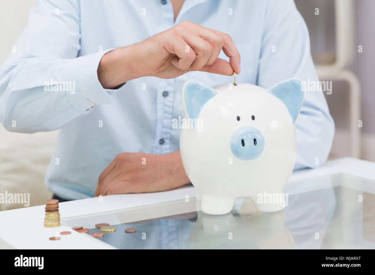 Mid section of a man putting some coins into a piggy bank Stock Photo ...