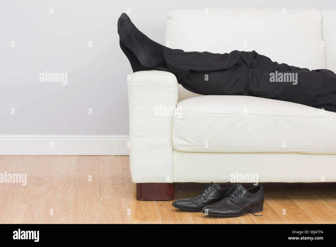 Low section of businessman resting on sofa in living room Stock Photo