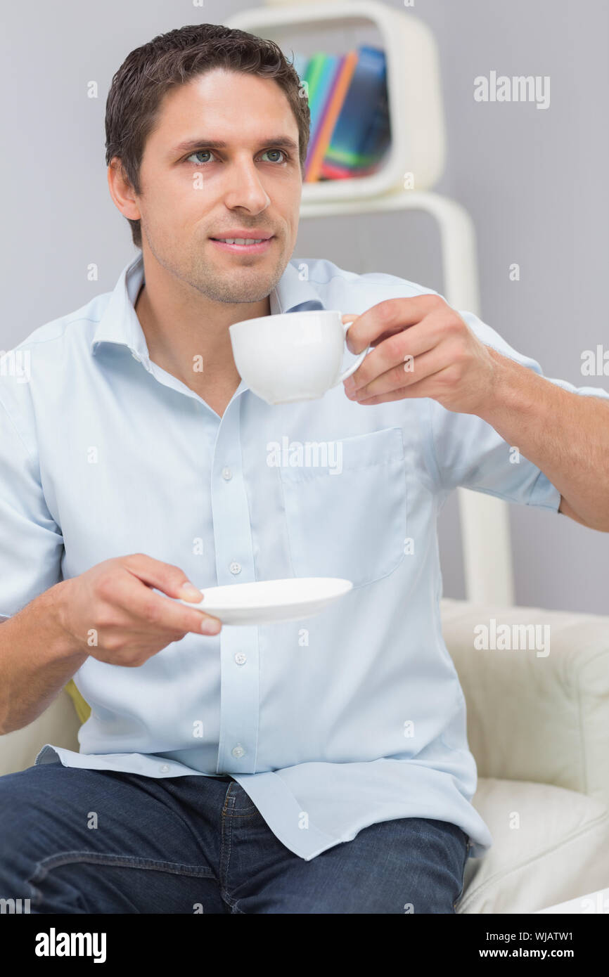 Thoughtful young man drinking tea at home Stock Photo
