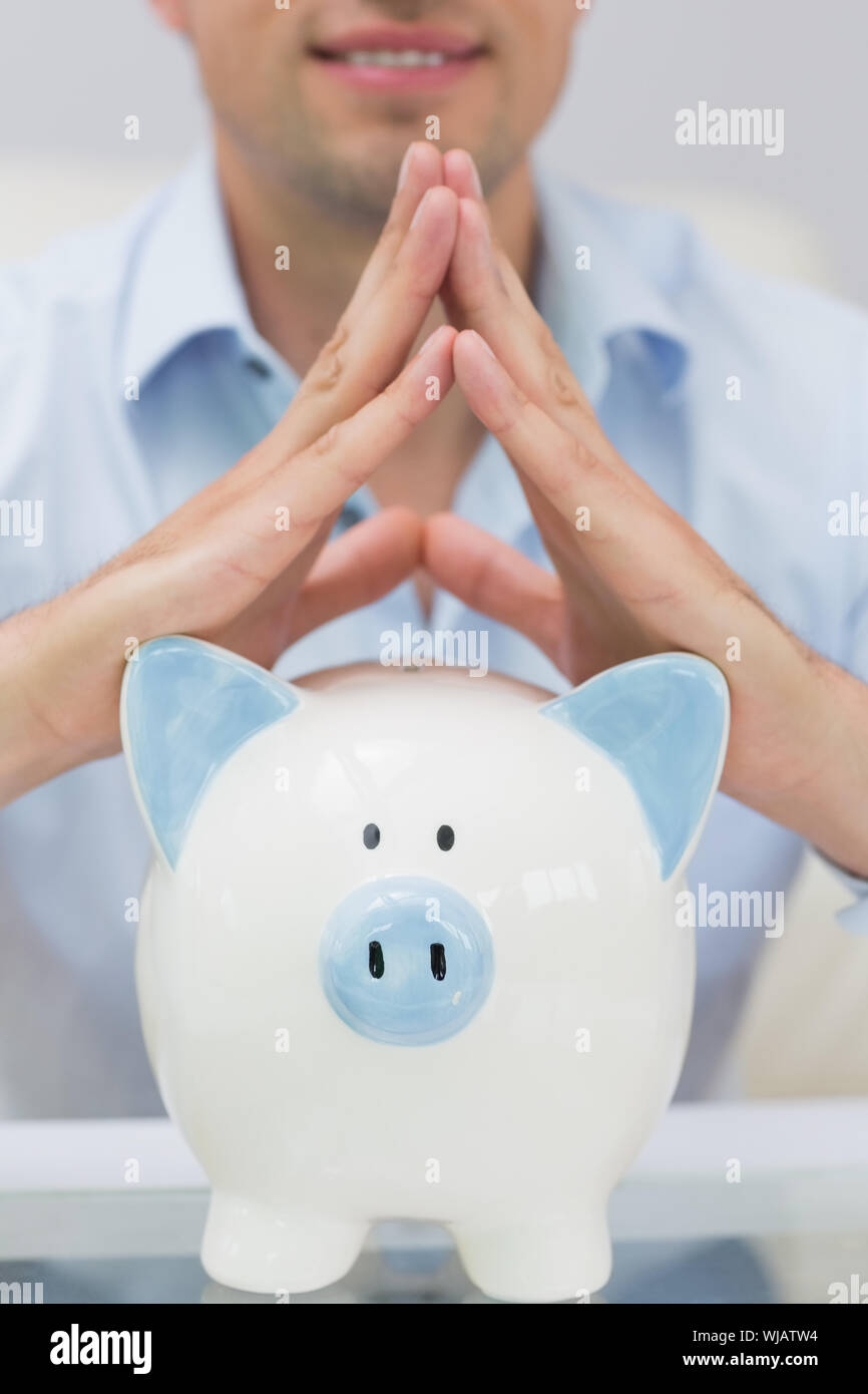 Close-up mid section man with piggy bank at home Stock Photo