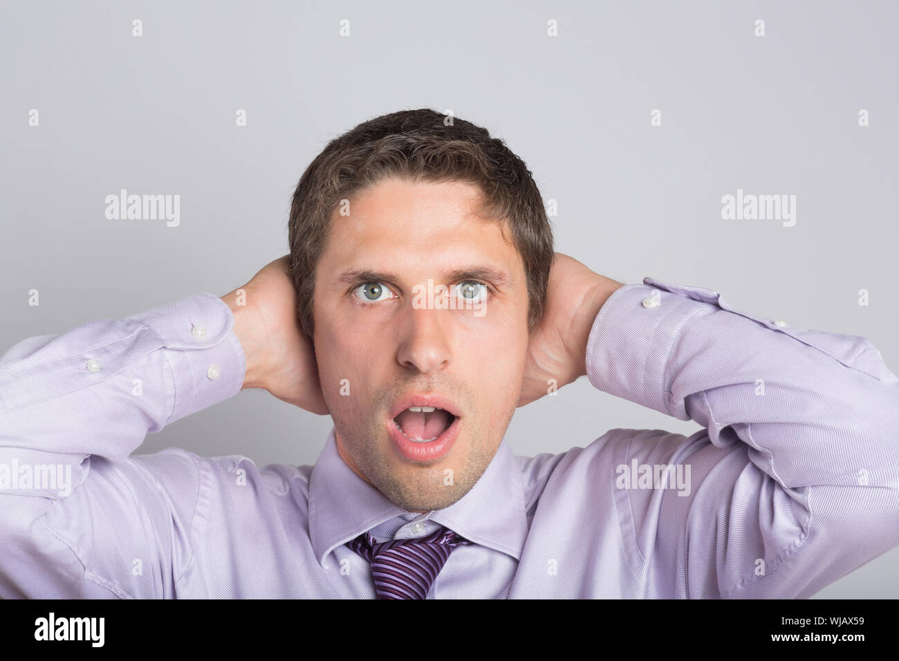 Green eyed businessman with hands covering ears Stock Photo Alamy