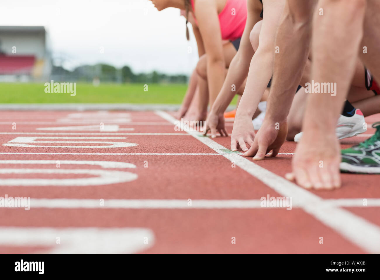 Side view of cropped people ready to race on track field Stock Photo
