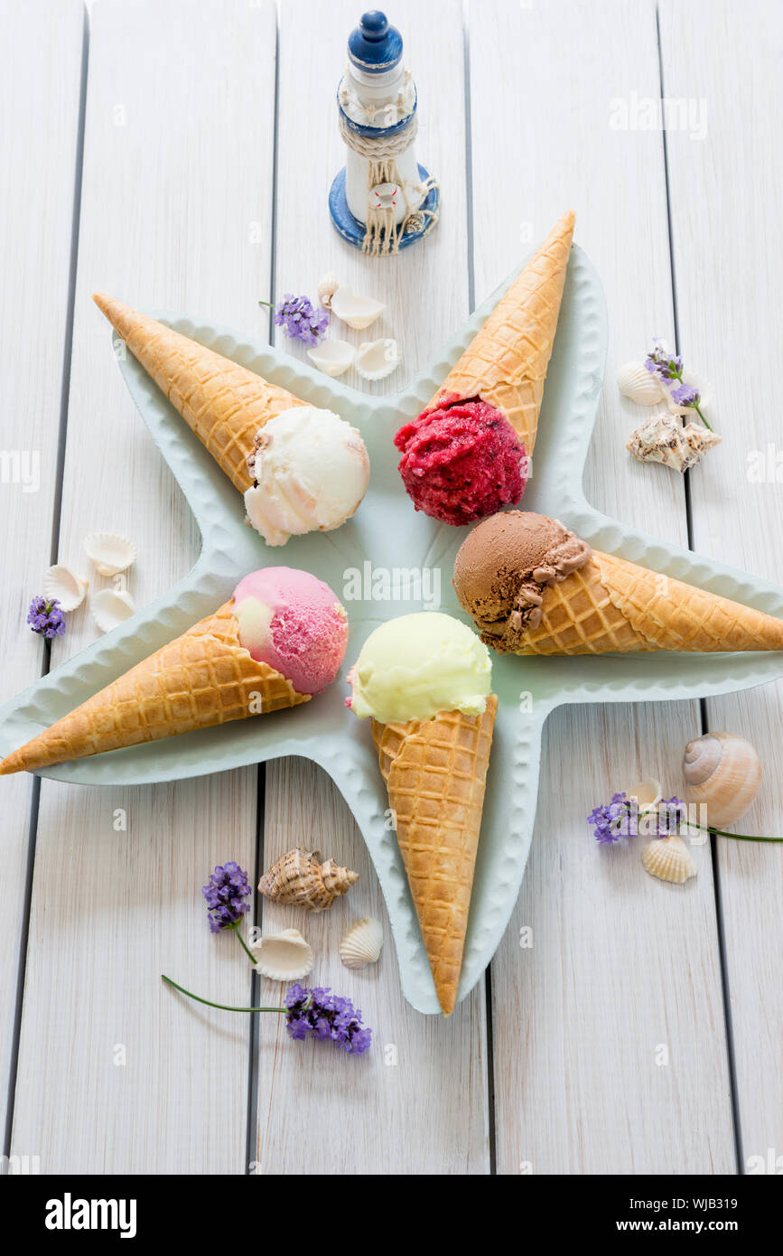 A variety of balls of ice cream in cones with chocolate, vanilla and strawberries Stock Photo