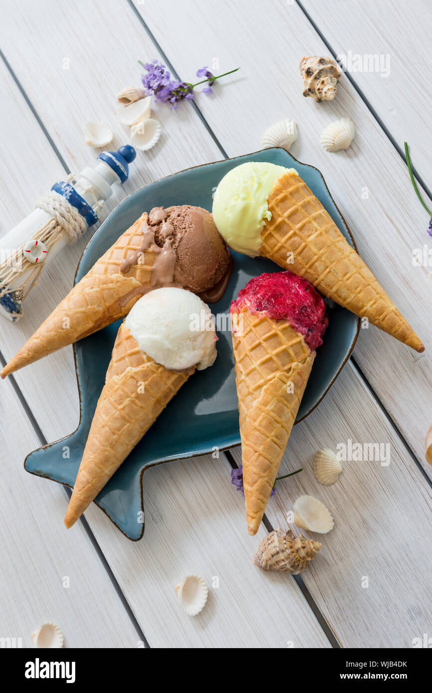 A variety of balls of ice cream in cones with chocolate, vanilla and strawberries Stock Photo