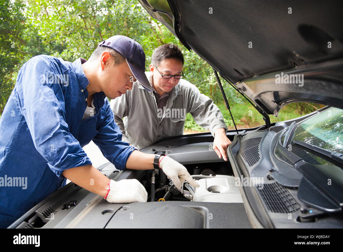 two Mechanics fixing the car on the road Stock Photo - Alamy