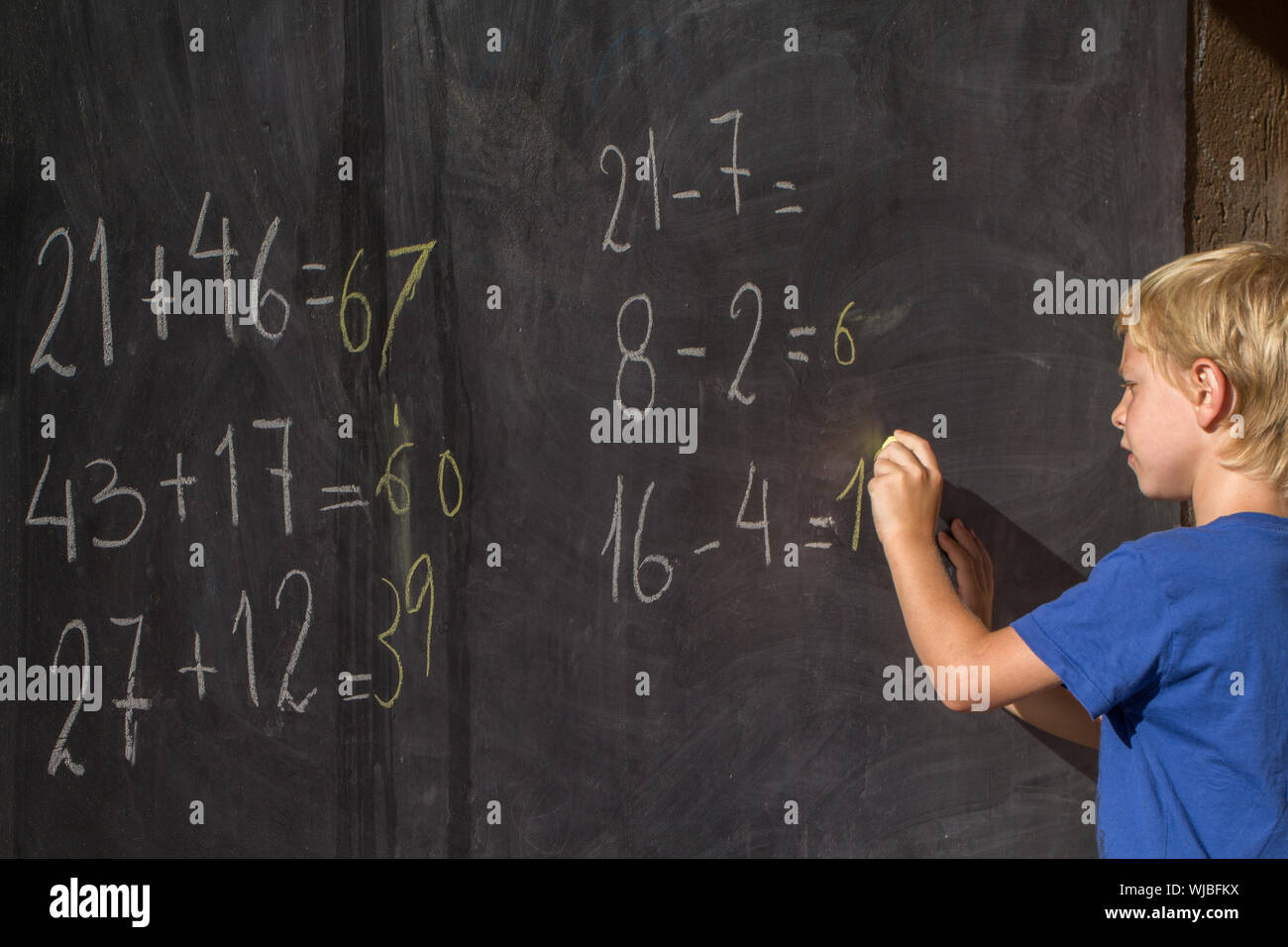 Boy Solving Mathematics On Blackboard Stock Photo