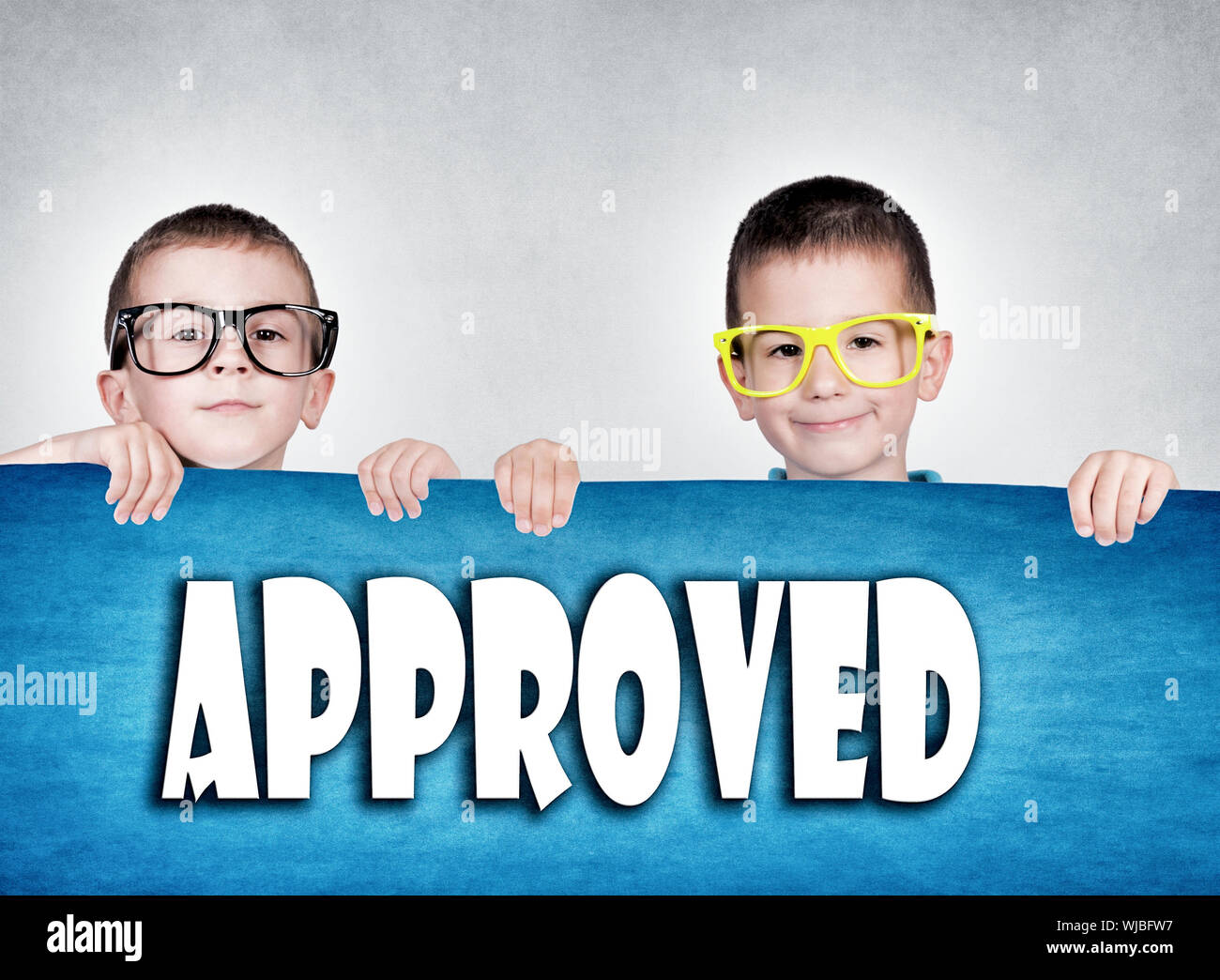 Twins holding blank red poster with approved sign Stock Photo