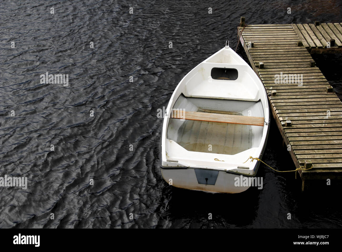 An old white rowing boat at a timber jetty Stock Photo