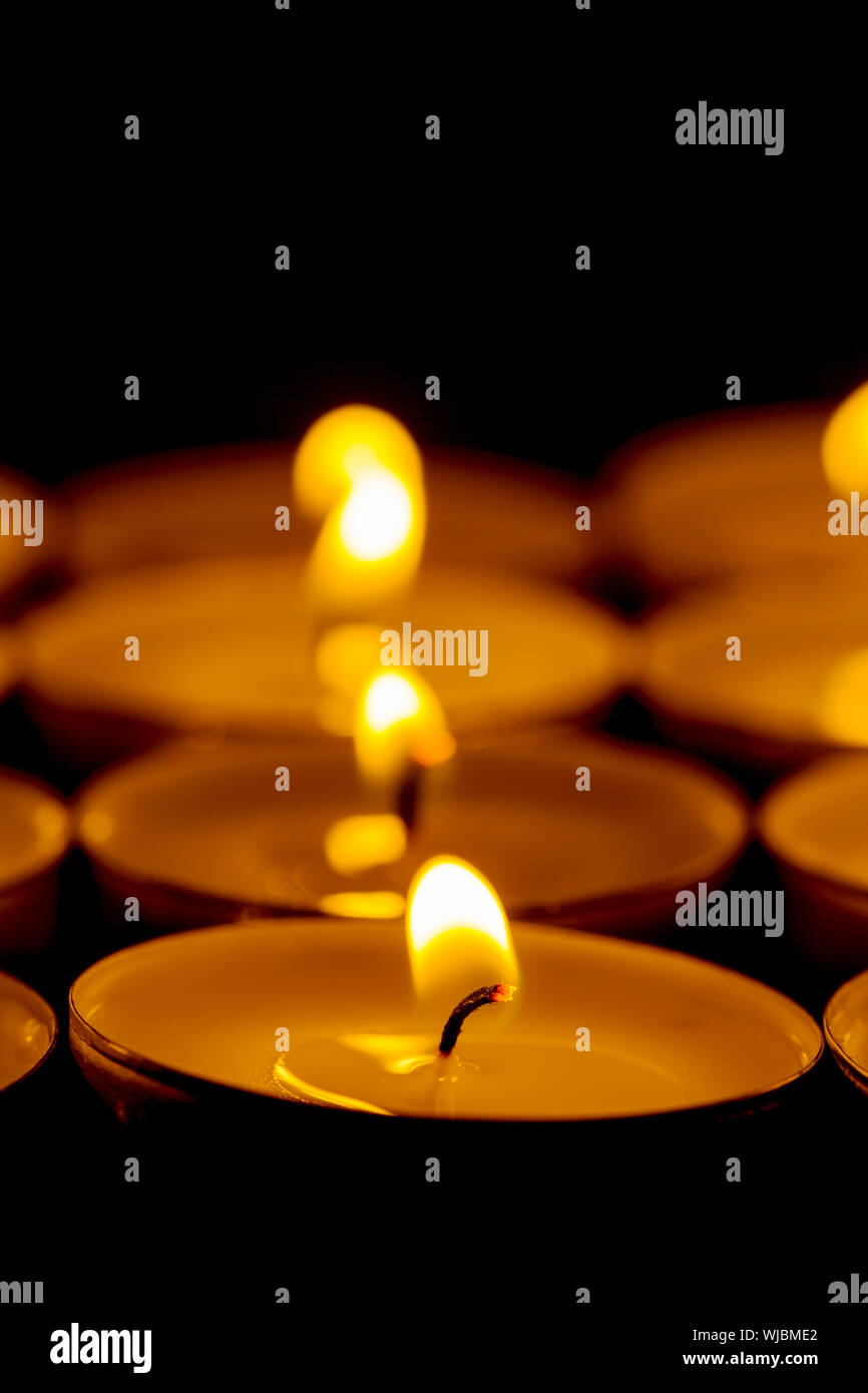 Tea lights candles with fire on dark background Stock Photo Alamy