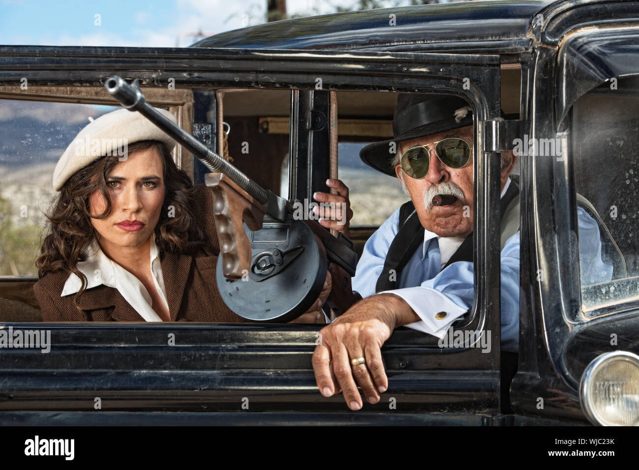 Pair of 1920s vintage gangsters waiting inside an antique car Stock Photo