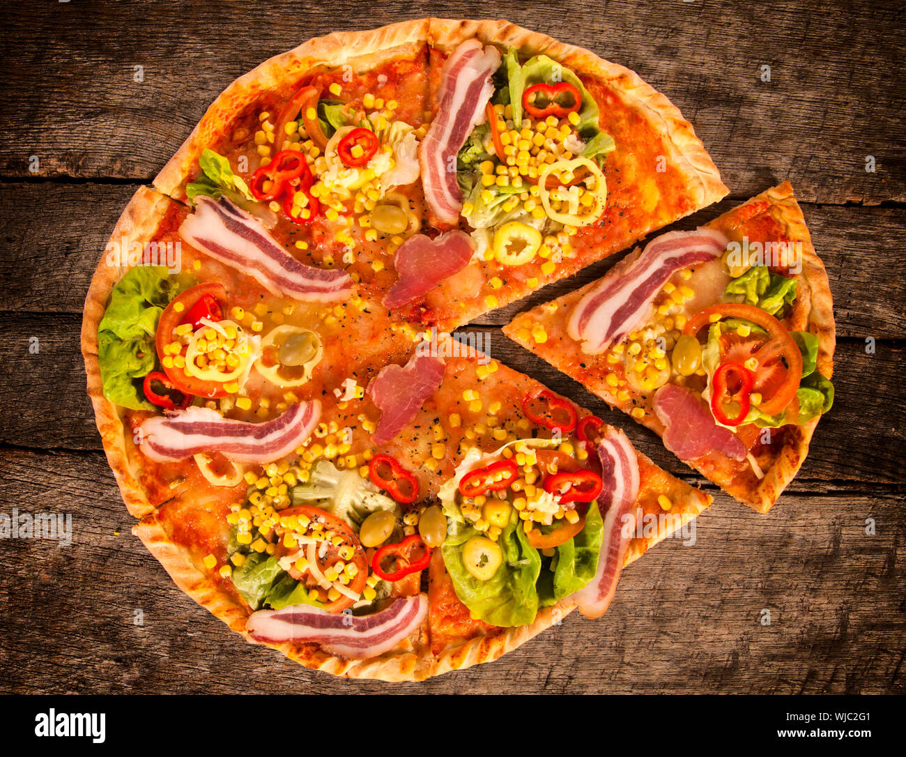 Whole gourment pizza on the wooden table, from above Stock Photo