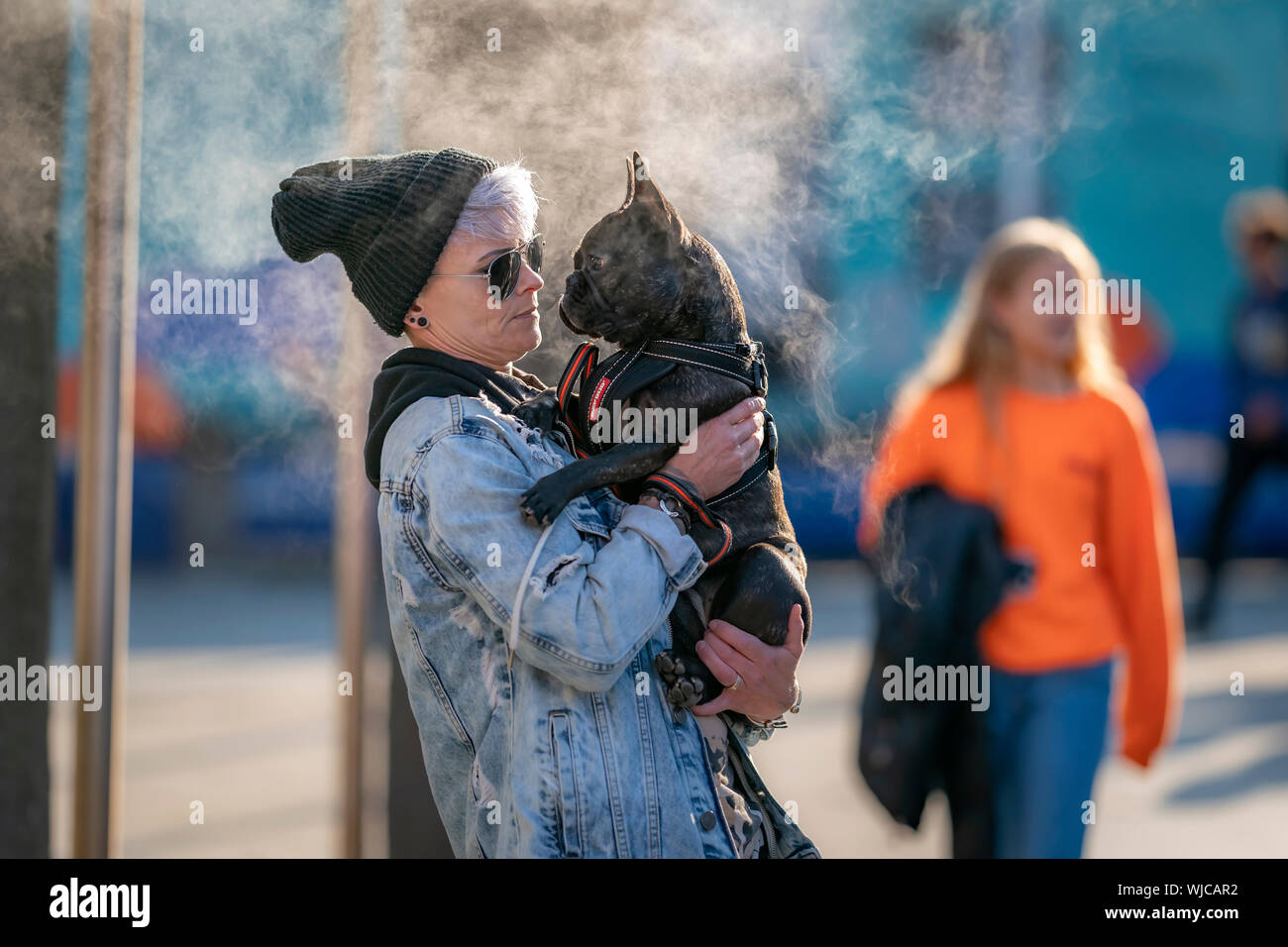 Woman holding a french bulldog, steam in background, Menningarnott or Cultural day, Reykjavik, Iceland. Stock Photo