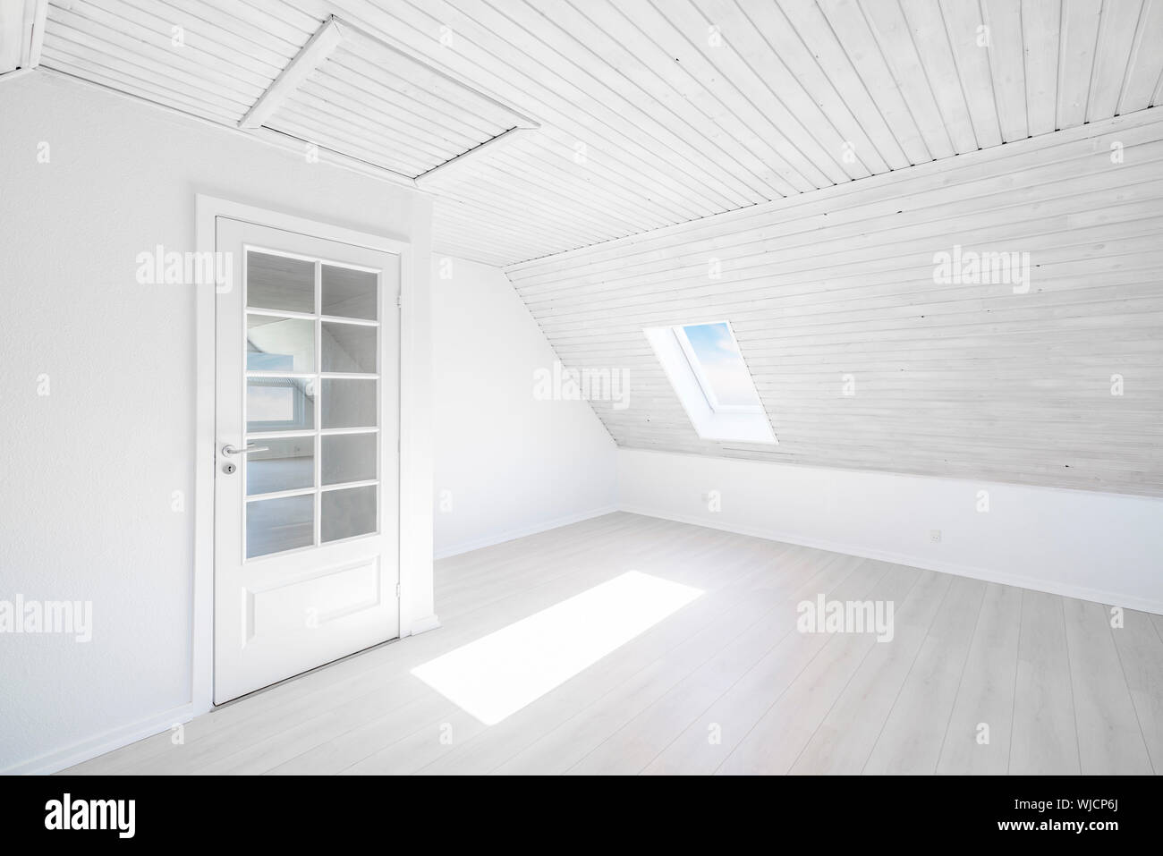 Bright room with the sun shining through a small window in a wooden apartment with a glass door Stock Photo