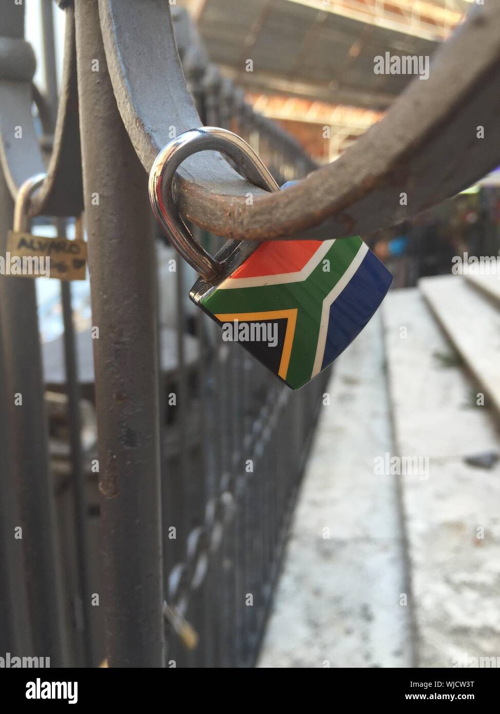 Closeup Of Padlocks With South African Flag Hanging On Railing Stock