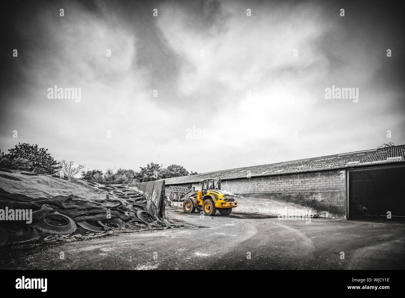 Yellow excavator at a construction site in dramatic cloudy weather ...