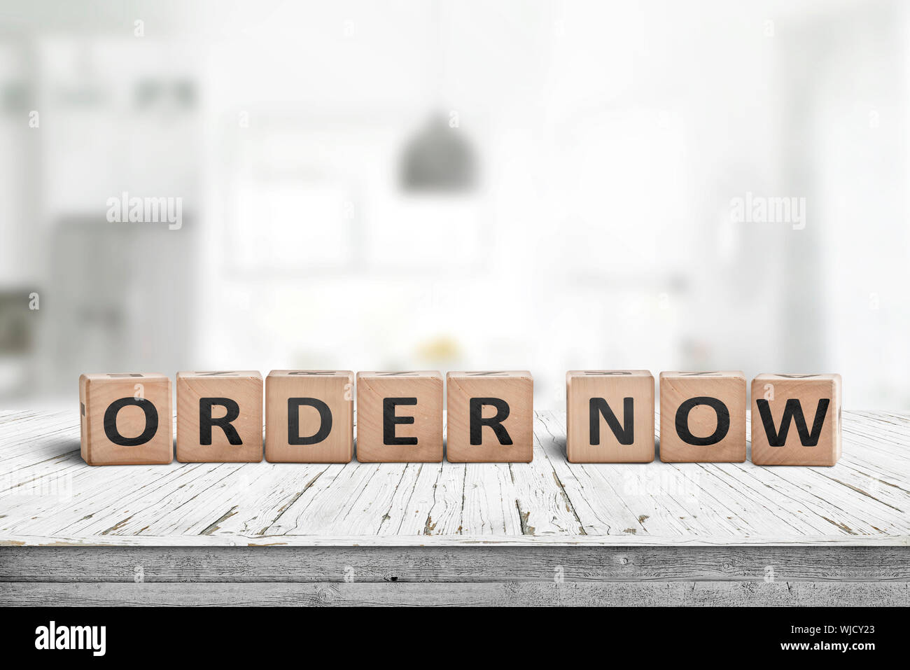 Order now sign on a wooden table in a brigh living room with interiors Stock Photo