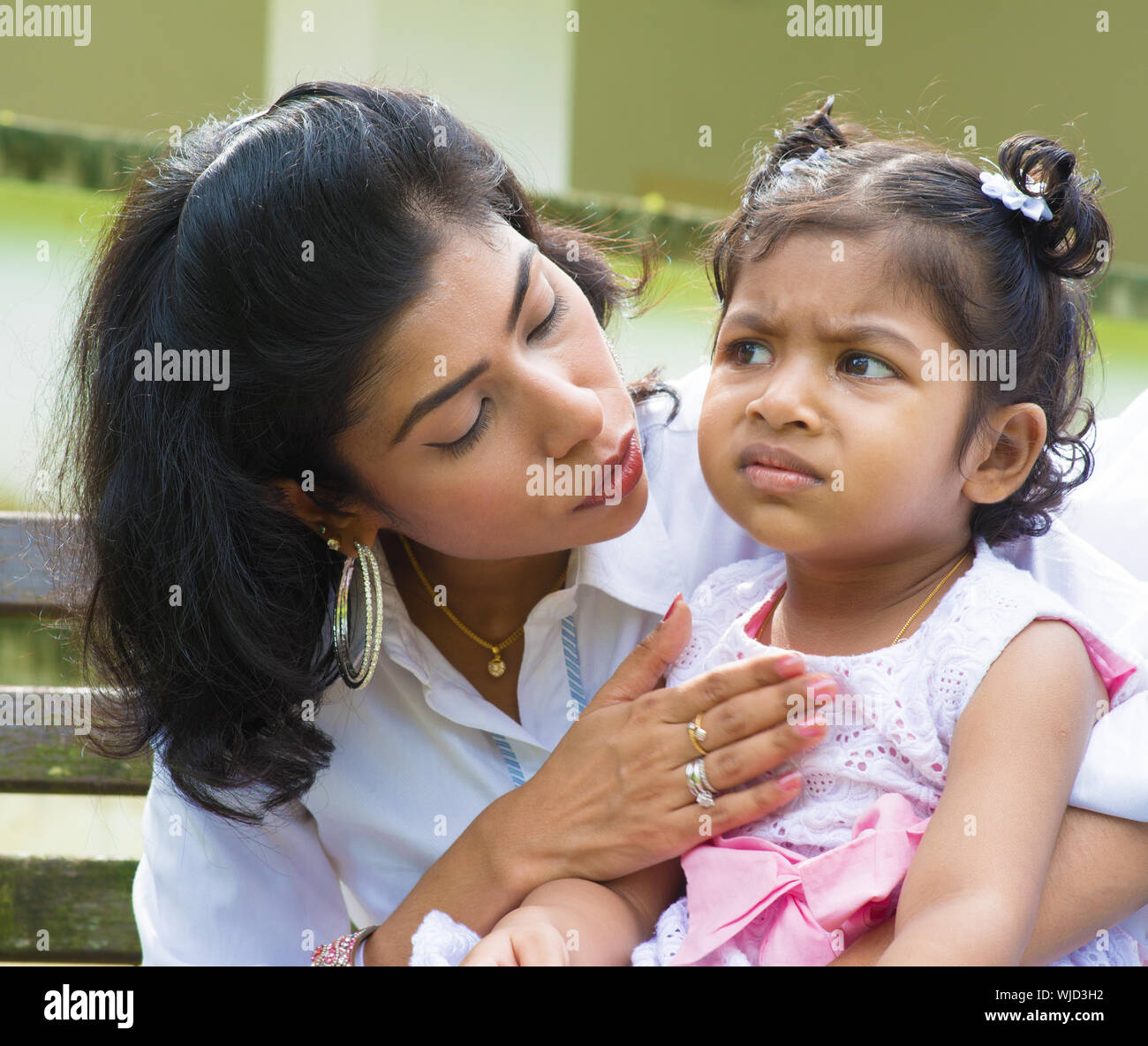 Indian family outdoor. Modern mother is comforting her crying daughter. Stock Photo