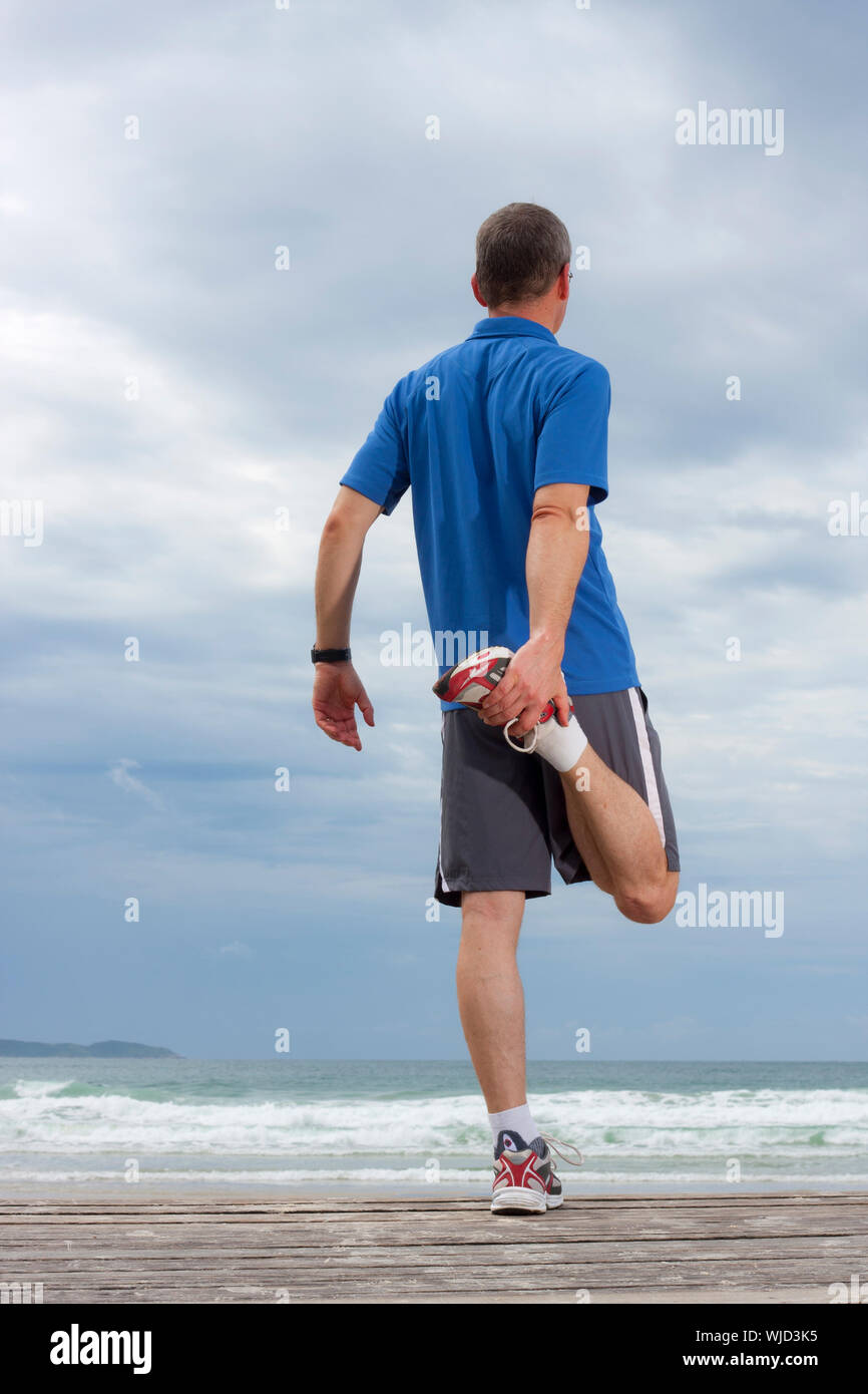 Runner doing stretching exercise on a beach Stock Photo