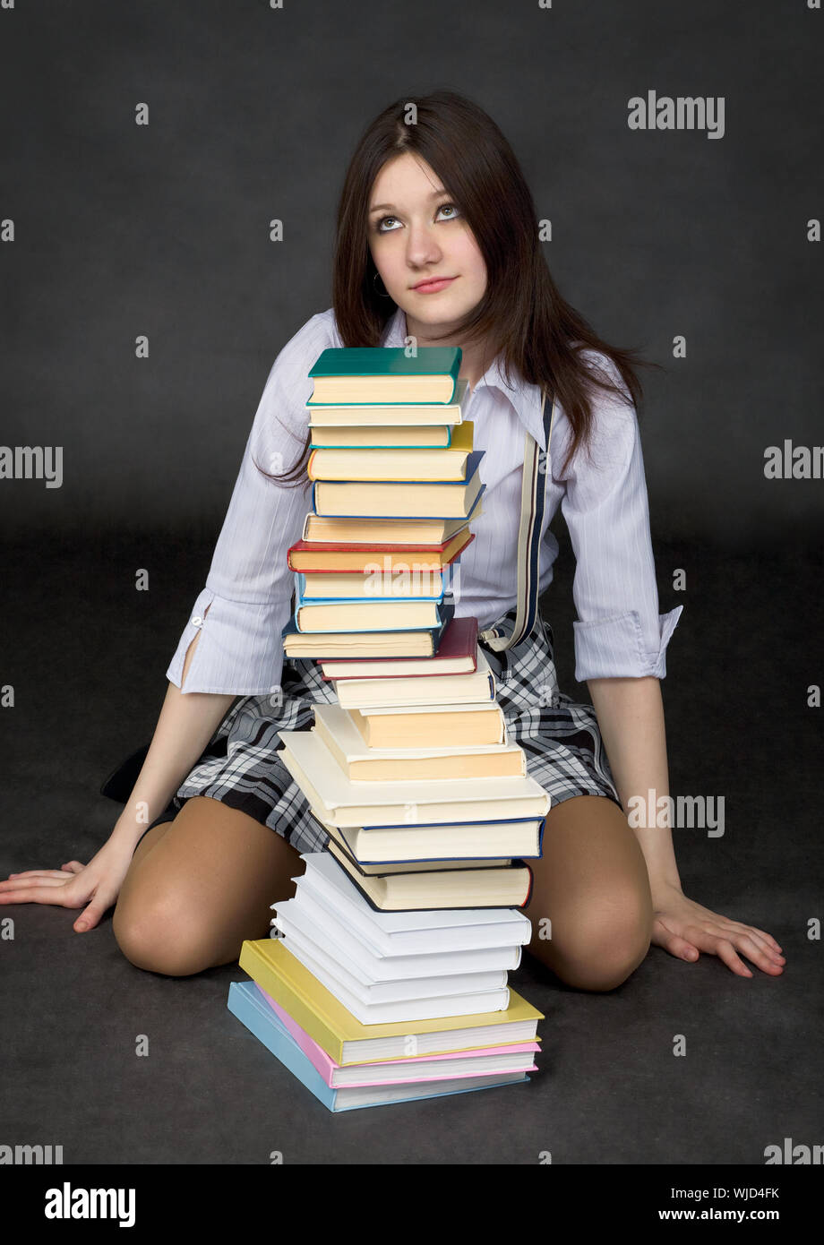 Schoolgirl and the big pile of books on a black background Stock Photo ...