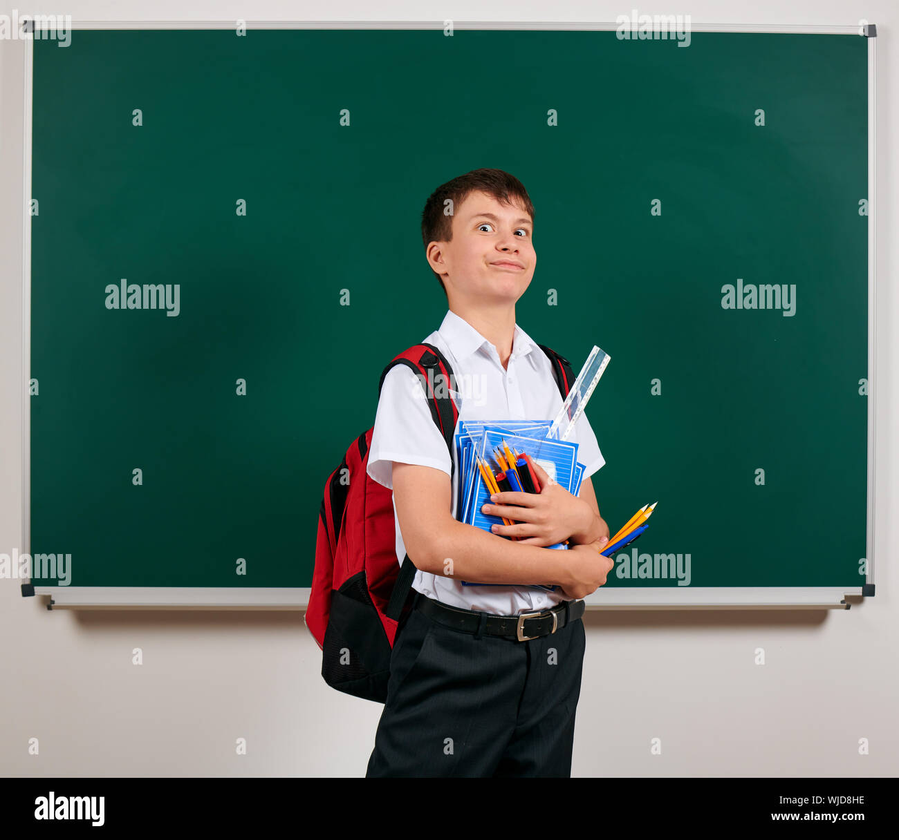 Portrait of a school boy posing with backpack and school supplies ...