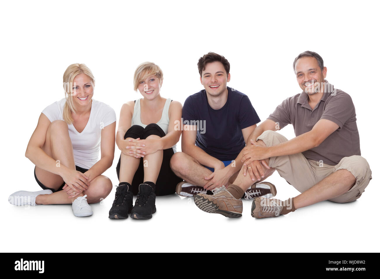 Happy friendly family with a teenage son and daughter lying in a row on the floor on their stomachs relaxing resting on their elbows Stock Photo