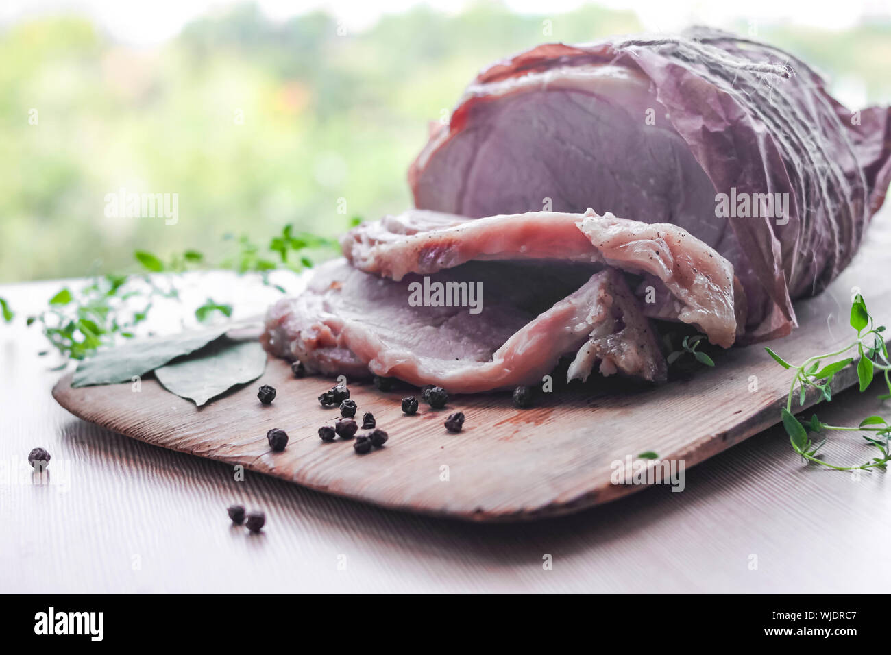 Homemade baked pork ham on rustic cutting board with aromatic ...