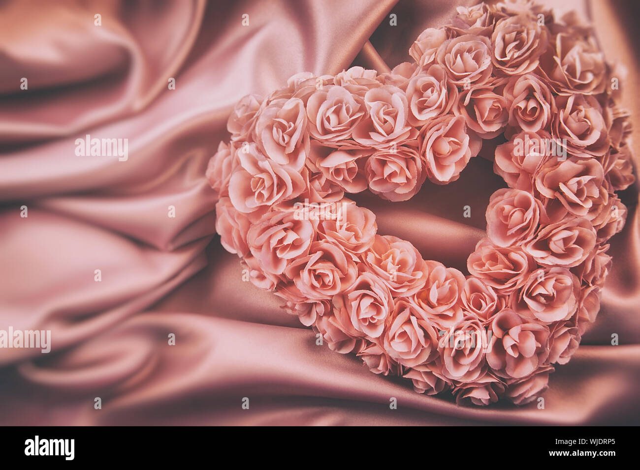 Heart made of pink roses on satin Stock Photo - Alamy
