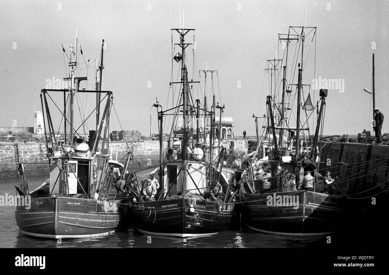 Fishermen working on boats, Saturday morning, Seahouses harbour, c.1972 Stock Photo
