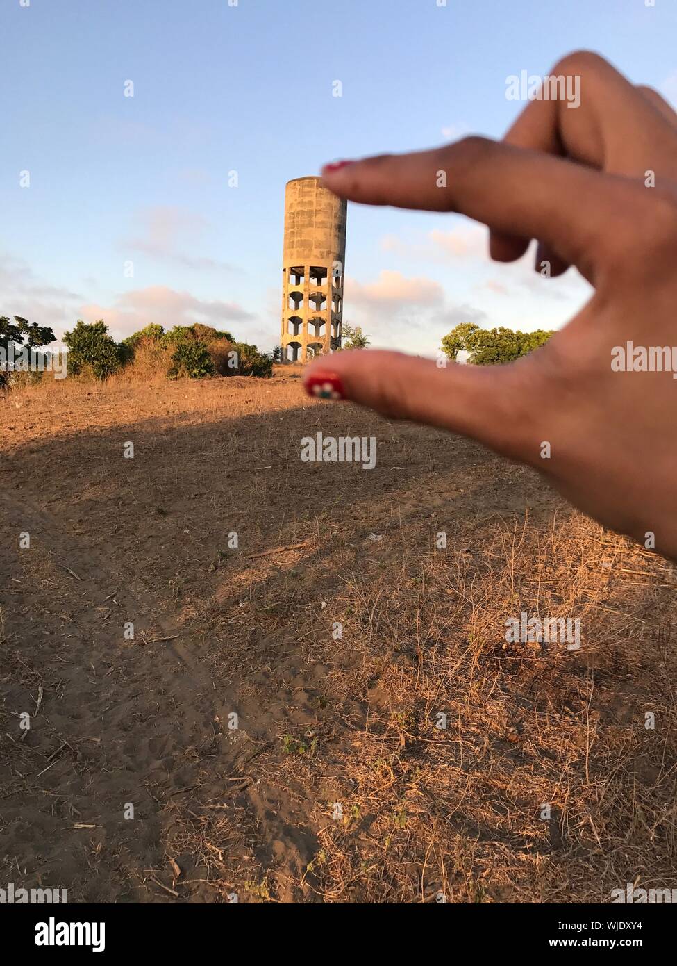 Optical Illusion Of Woman Holding Water Tank Against Sky Stock Photo